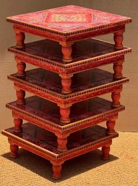 Hand-painted red Bajot Chowki low tables stacked showing painted floral medallion top