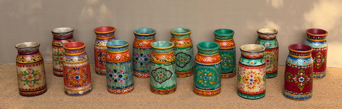 Collection of hand-painted Rajasthani mango wood milk pot vases in vivid folk art jewel tones — each one unique