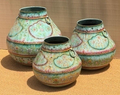 Set of three graduated hand-painted Rajasthani metal pots in aged celadon sage green with scalloped ogee floral cartouches, dusty rose shoulder band and brass ring handles