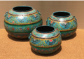 Set of three graduated hand-painted Rajasthani metal pots in vivid turquoise-teal with gold swag festoon arches, dark leaf scroll, pink and red flowers and iron ring handles
