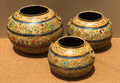 Set of three graduated hand-painted Rajasthani metal pots in warm golden-ochre with Mughal garden painting featuring large flowers, birds, butterflies and blue dot-work separator band with iron ring handles