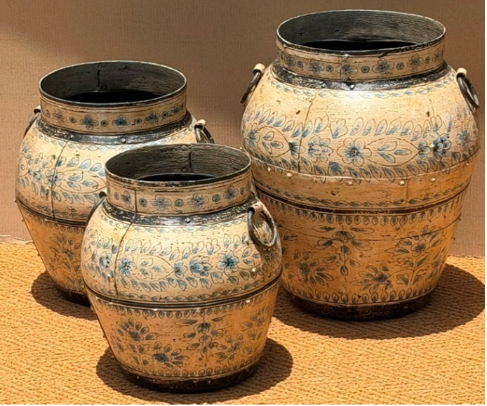 Set of three graduated hand-painted Rajasthani metal pots in aged parchment cream with delicate blue-grey floral, iron dome nail stud separator band, heavy dark patina at rim and base and iron ring handles