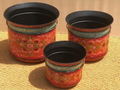 Set of three hand-painted metal planters in coral-red vermillion with dense gold and pink floral all-over, teal sage-green shoulder band, matte black rim and interior, and two small brass ring handles each