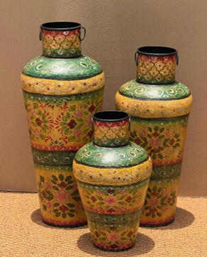 Three hand-painted metal floor vases in ivory cream with teal green scrolling vine shoulder band, scattered pink red floral mid-body, terracotta dot-work lower band and dark crosshatch base — sizes 73 cm, 63 cm and 49 cm