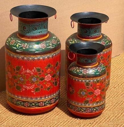 Set of three hand-painted metal canister vases in bold coral-red vermillion with teal dark green scrolling vine collar band, scattered pink white multicolour floral body, gold teal shoulder and base banding, and iron ring handles at rim
