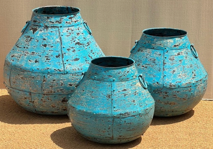 Set of three distressed iron wide-shoulder pots in heavily cracked and chipped sky blue turquoise finish with riveted panel seams radiating from neck, wide flat shoulder dropping to narrow base and iron ring handles on each side