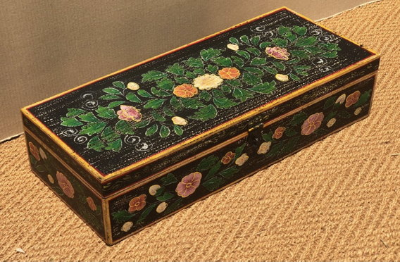 Hand-painted mango wood keepsake box in jet black with gold border banding, open airy floral cluster lid with white pink orange blooms and dark green foliage, large scattered pink mauve flowers on body panels and four bracket feet