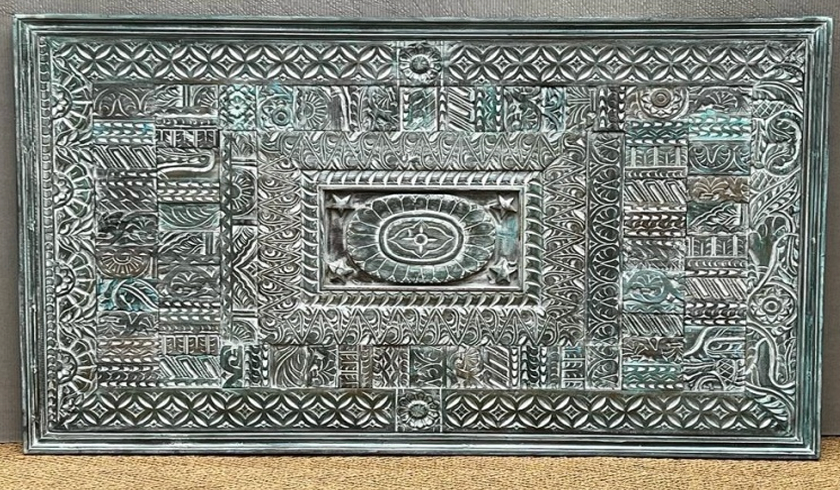 Large antique teal-green carved mango wood wall panel with geometric angular patchwork relief motifs and central rope-twist framed oval medallion