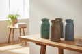 Four distressed colour-wash wood vases grouped on timber console in Scandi-bohemian living room