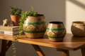 Two ivory cream round belly planters on warm timber shelf with trailing plants