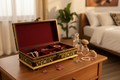Black and gold keepsake box open on warm timber dressing table with jewellery and perfume bottles