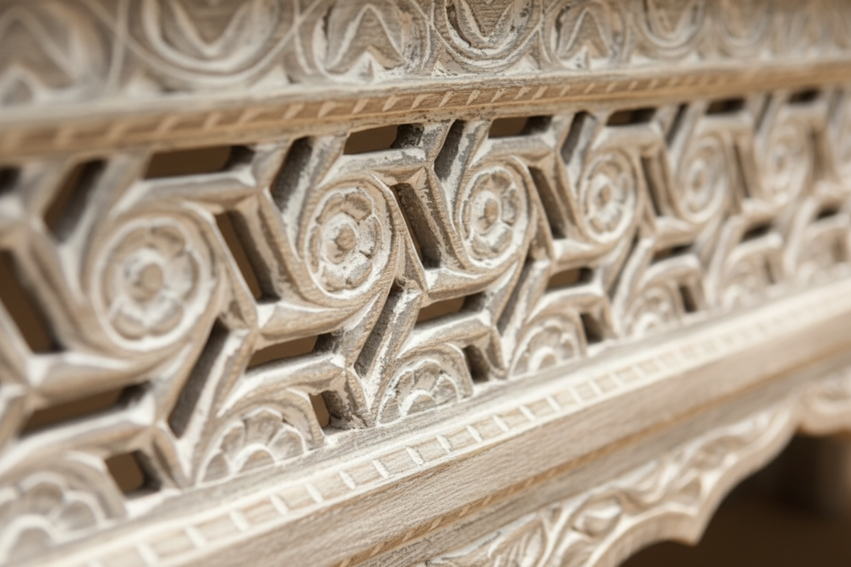 Close-up of hand-carved geometric fretwork and floral vine detail on whitewash console table