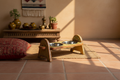 Butter yellow arch-leg Rajasthani dog bowl stand in warm Rajasthani living room with earthy textiles