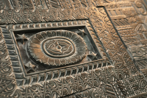 Close-up split detail: central rope-twist cartouche with oval medallion and geometric patchwork zones